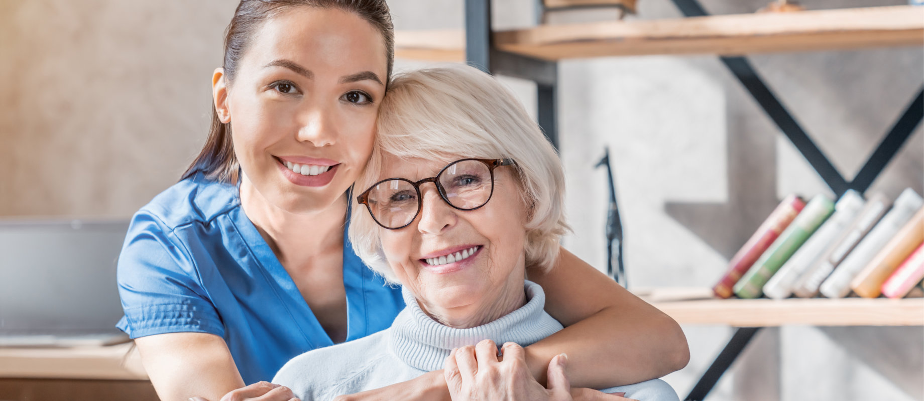 caregiver hugging senior woman from the back